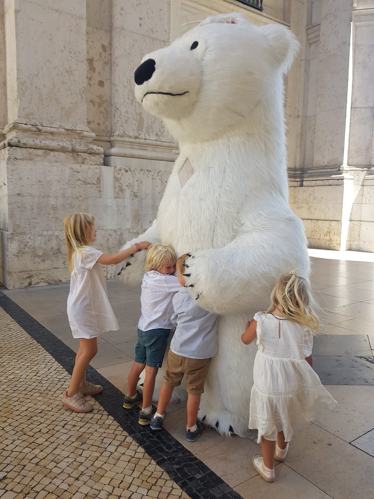 Children spontaneously hugging a giant polar bear on a Lisbon street