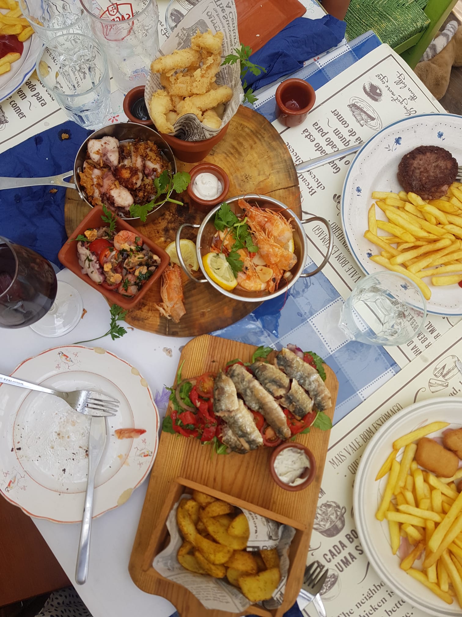 Overhead view of a family seafood feast — prawns, sardines, and laughter