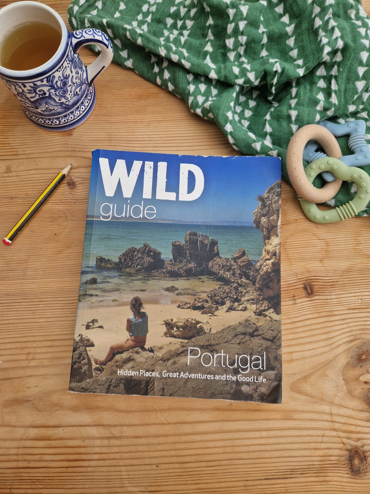 Wild Guide Portugal book on a wooden table with a cup of tea — the kind of research that goes into every trip